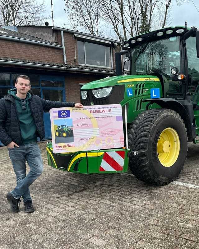 Geslaagd voor het T-rijbewijs: cursist staat ontspannen naast het rijbewijsbord bij de lestrekker
