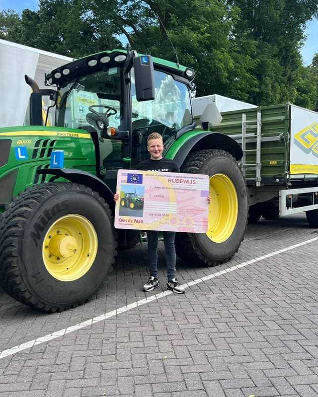 Geslaagde cursist met rijbewijsbord voor de lestrekker en de lesvrachtwagen van Kees de Vaan