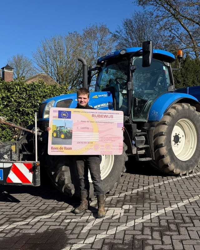 Geslaagd voor het T-rijbewijs: cursist met rijbewijsbord voor een blauwe lestrekker